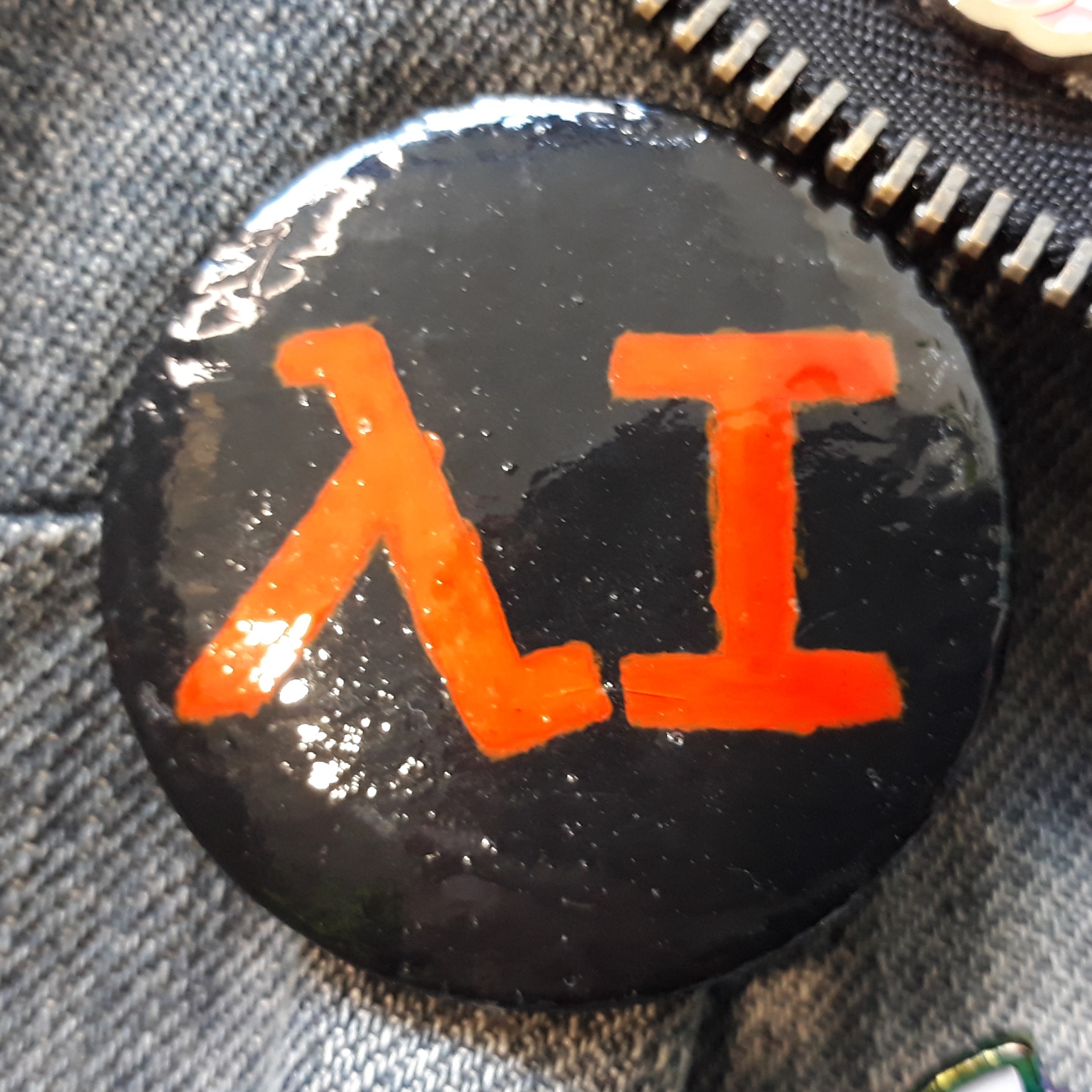 A black badge with orange writing spelling out 'AI’, using a lambda symbol for the A.